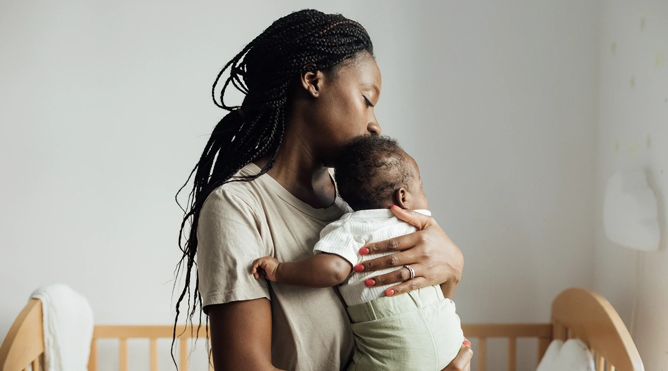 tired mom holding baby in nursery