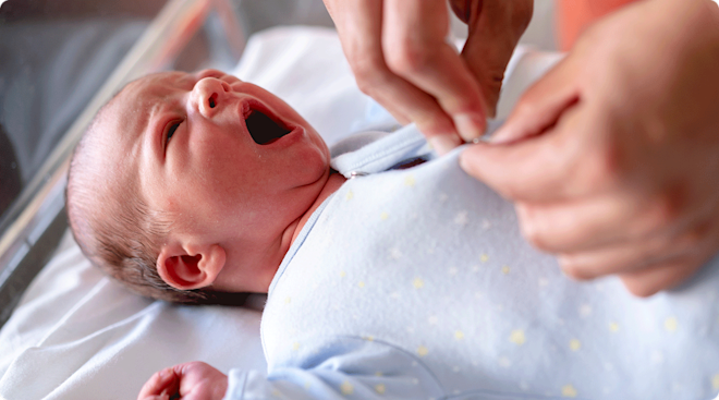 putting onesie on newborn baby in hospital