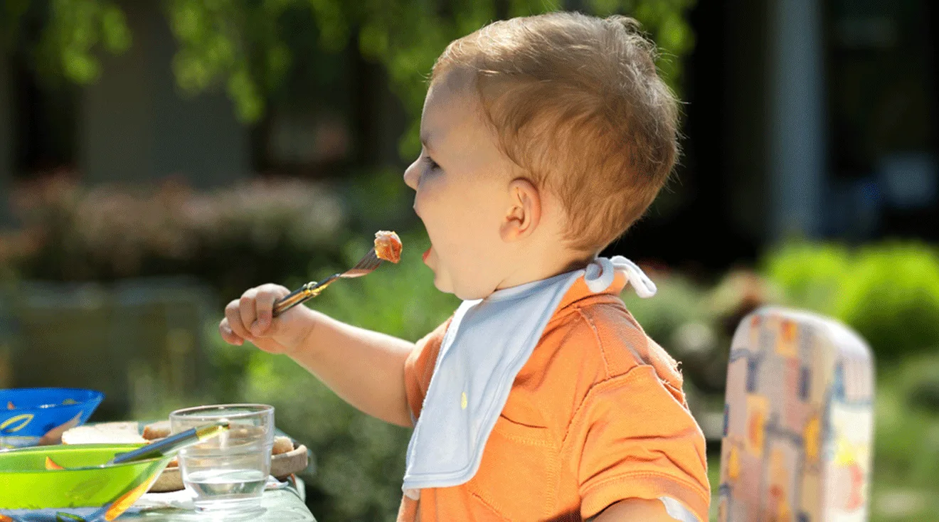 toddler eating at a table outside during summer