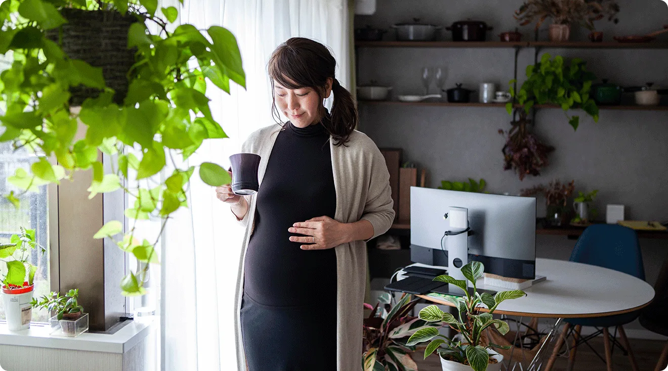 pregnant woman holding a cup of tea at home