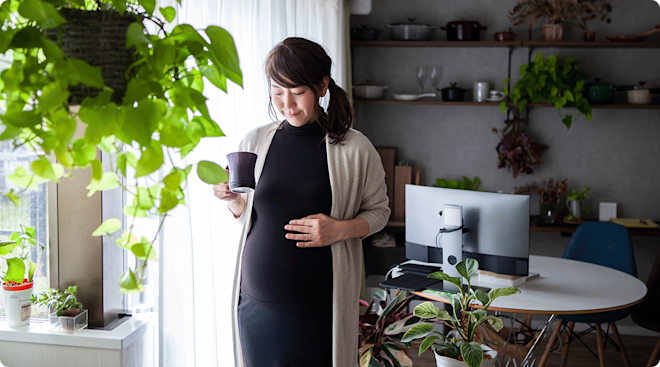 pregnant woman holding a cup of tea at home