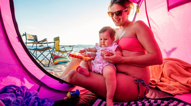 Toddler in a baby beach tent with mom