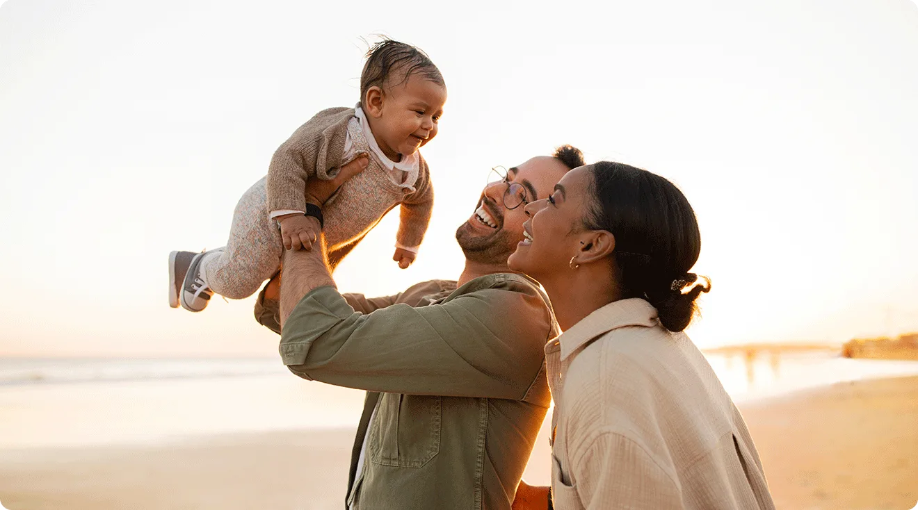 parents with baby at the beach during summer sunset