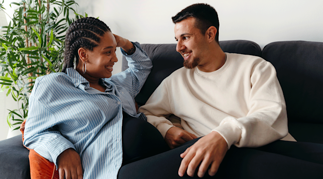 pregnant couple smiling on the couch at home