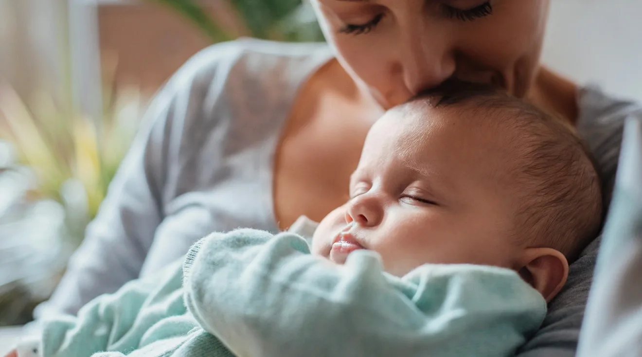 baby sleeping in mother's arms at home