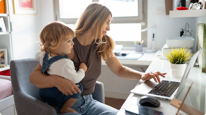 busy working mom on laptop while holding baby at home