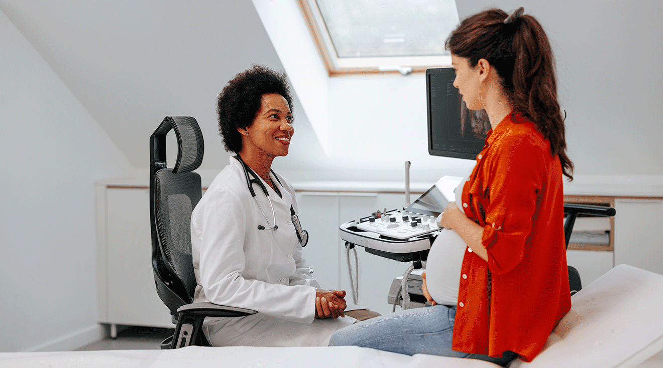 pregnant woman talking to doctor in exam room