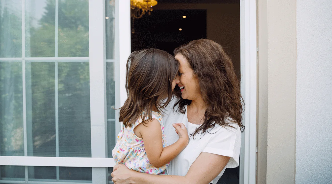 mom and toddler laughing outside of house