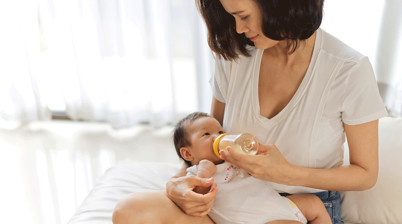 mother feeding formula bottle to baby