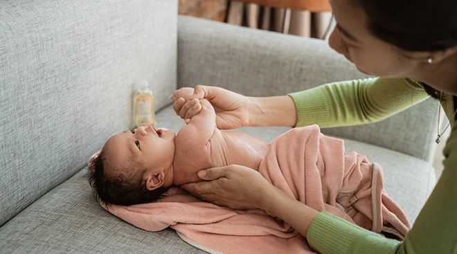mother applying lotion to baby's skin after bath