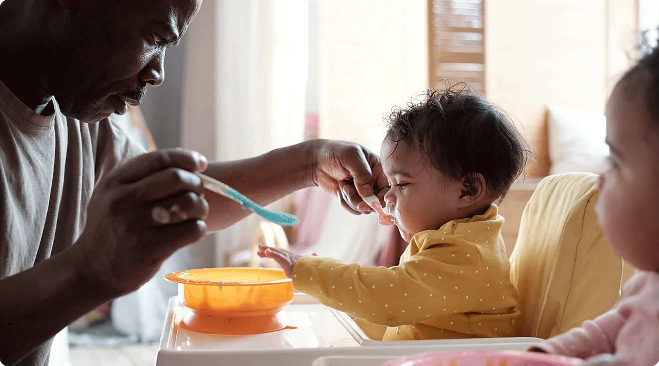 dad feeding daughters in high chairs
