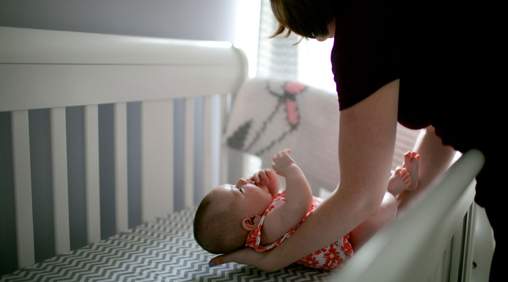 mom puts baby down for nap in crib