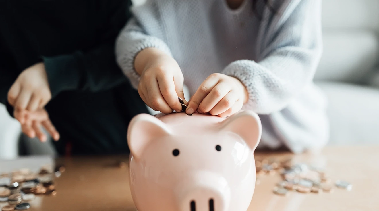 children putting coins into piggy bank