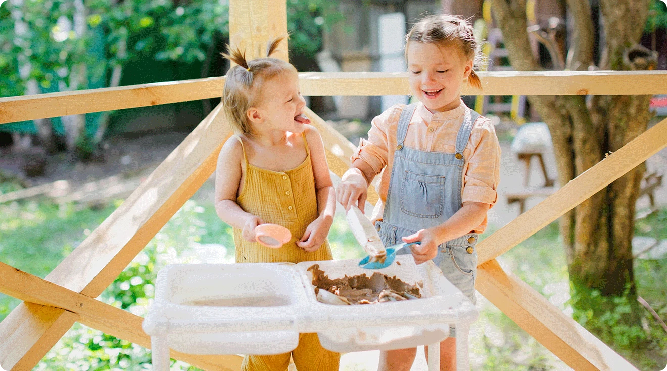 two children playing with sensory bin outside during the summer
