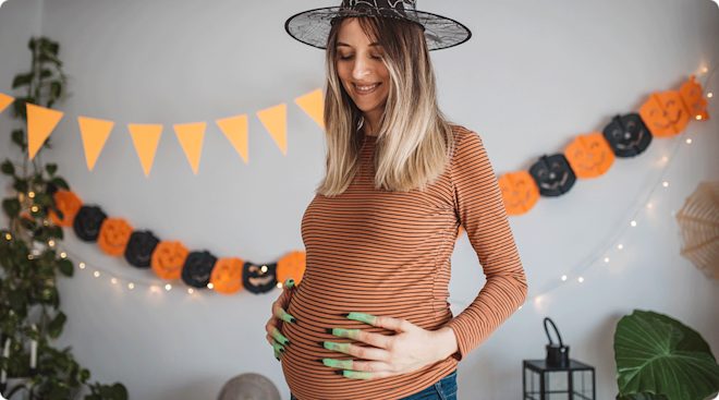 A pregnant woman dressed as a witch for halloween.