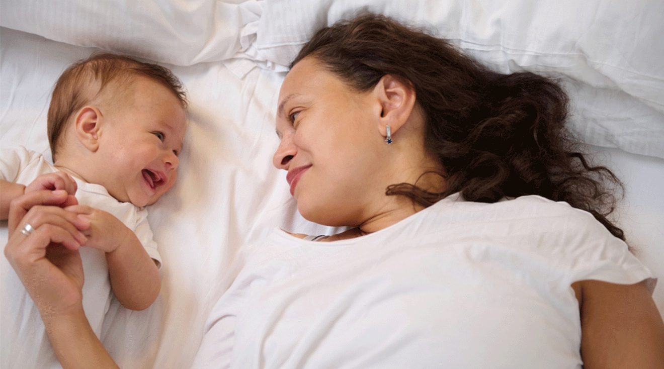 mom and baby smiling in bed