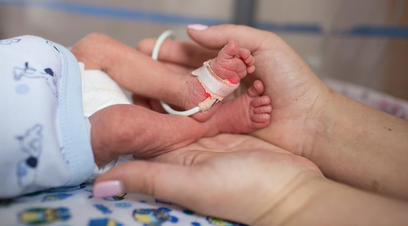 mother holding premature baby's feet while in hospital