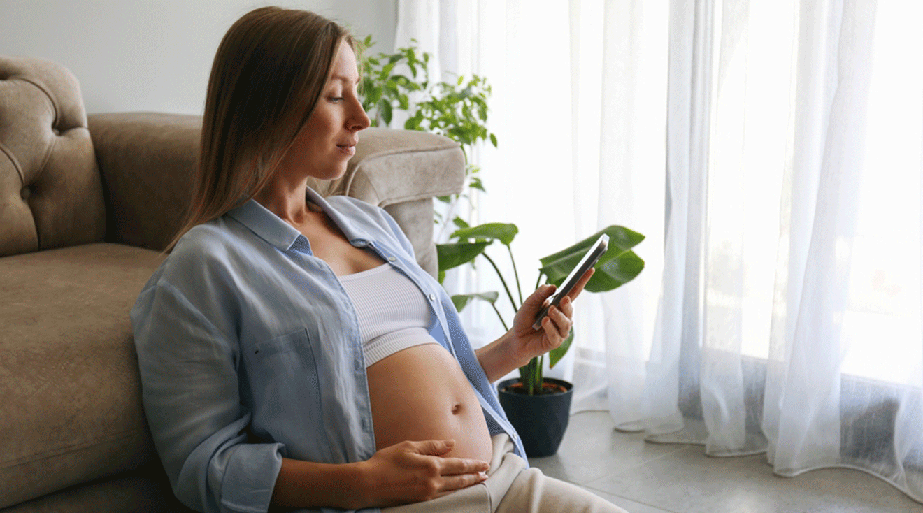 pregnant woman looking at phone while sitting at home