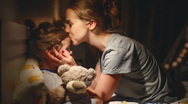 mother kissing toddler goodnight