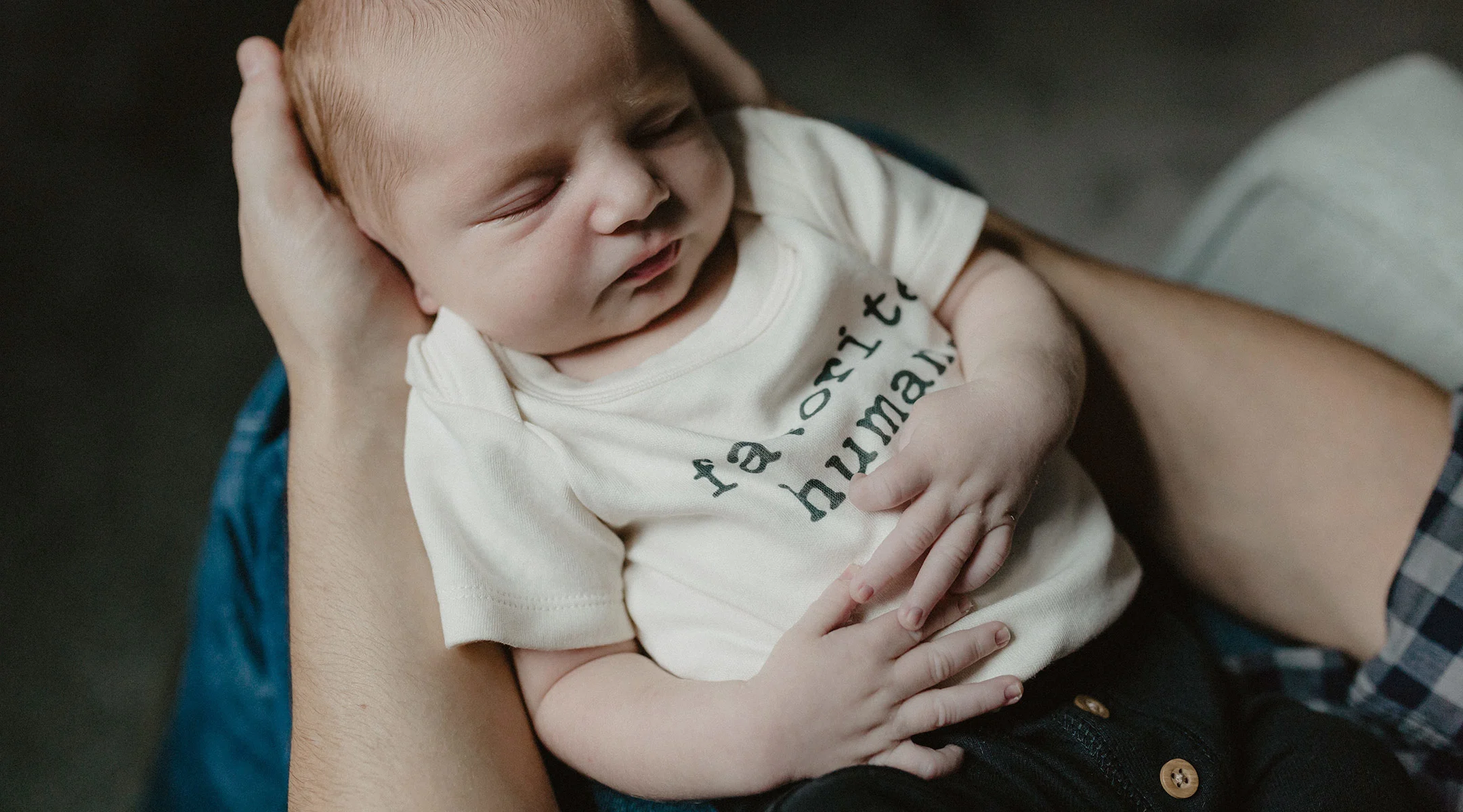 dad holds baby, who is wearing a t-shirt that says favorite human, in his arms