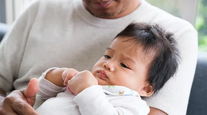 father holding baby at home on couch