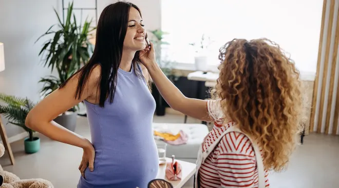 woman applying makeup to pregnant woman's face