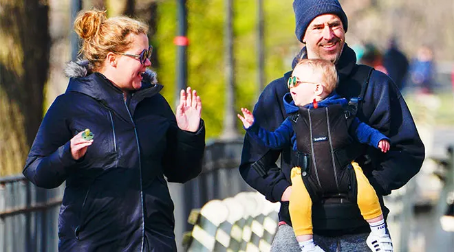 amy schumer with her bay son and husband walking in the park