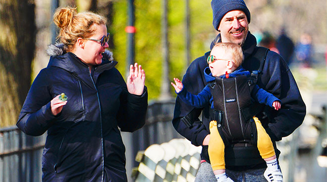 amy schumer with her bay son and husband walking in the park