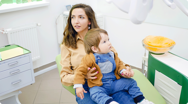 mom and baby sitting in dentist chair for baby's first dental check up