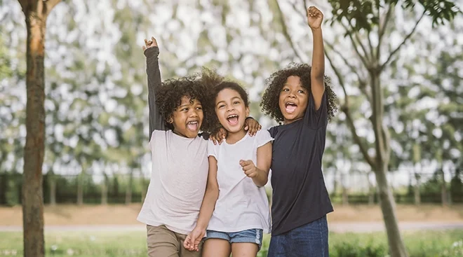 three proud and confident children smiling outside