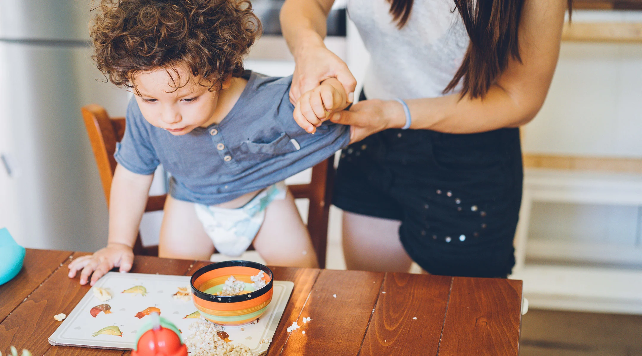 mom holding her toddler's arm after he spilled hi breakfast
