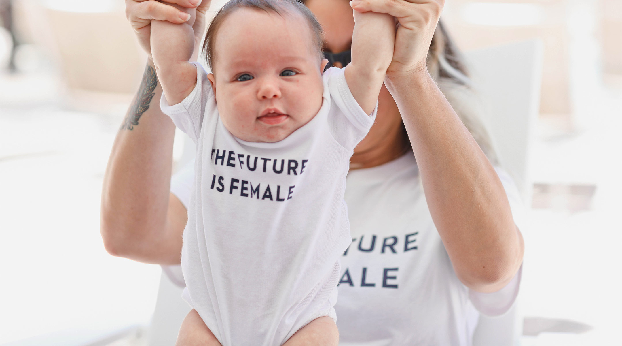 writer mom holding her baby daughter with onesie that says the future is female