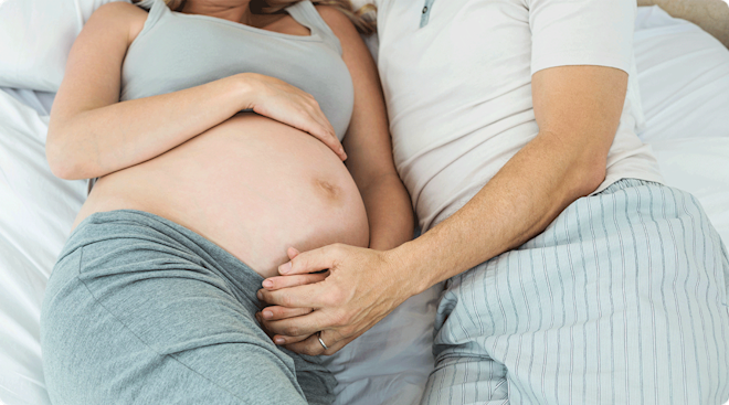 A pregnant intimate couple in bed together.