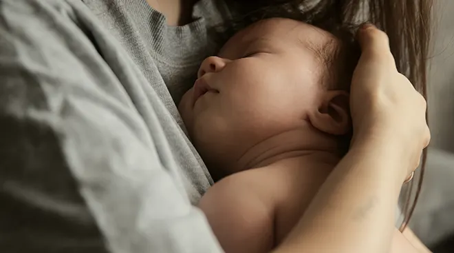 baby sleeping in mother's arms