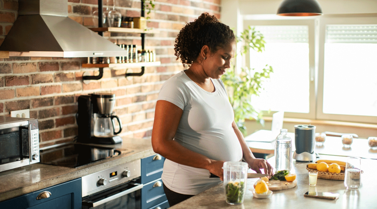 pregnant woman making a smoothie in the kitchen at home