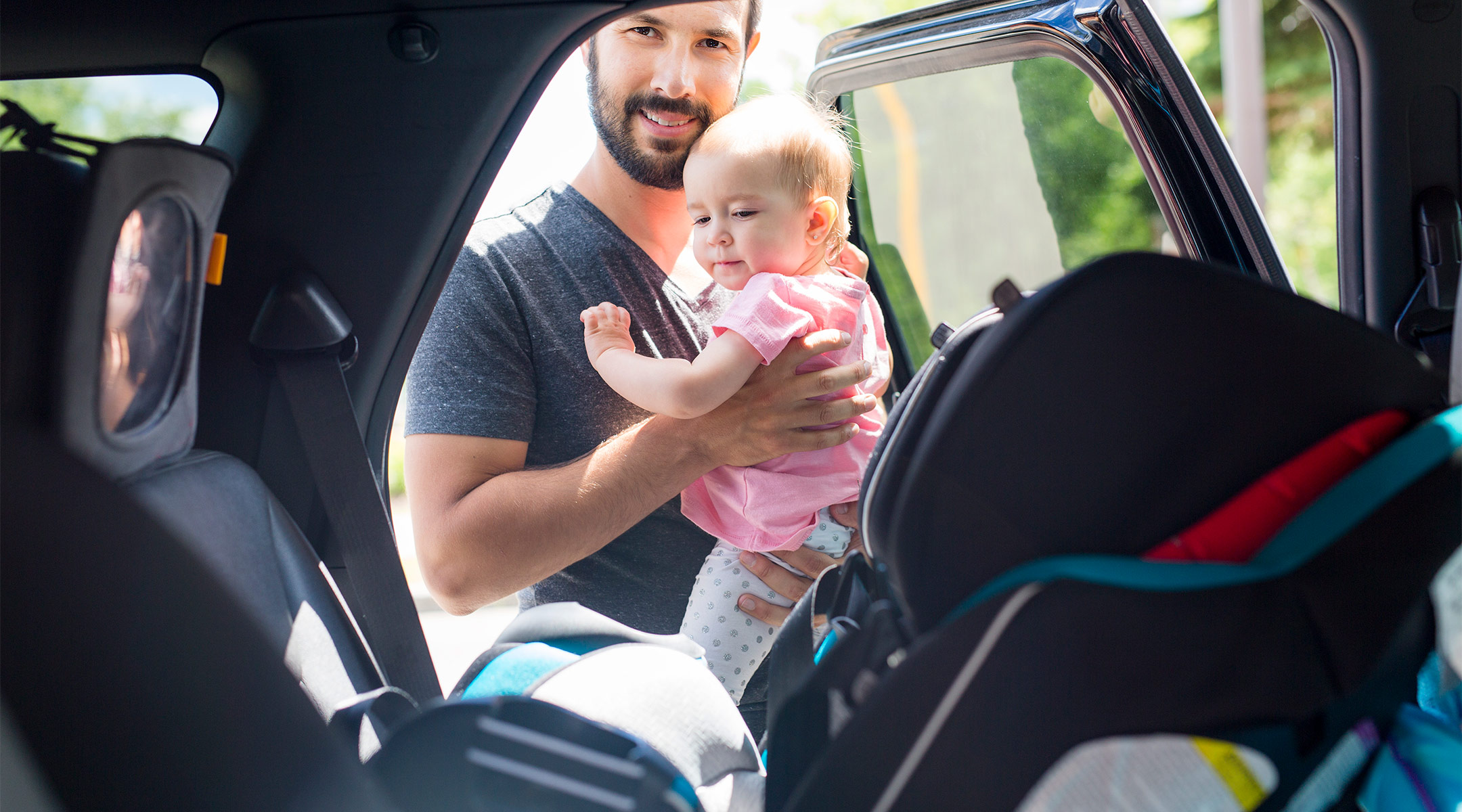 car seat safety, dad putting baby into her car seat