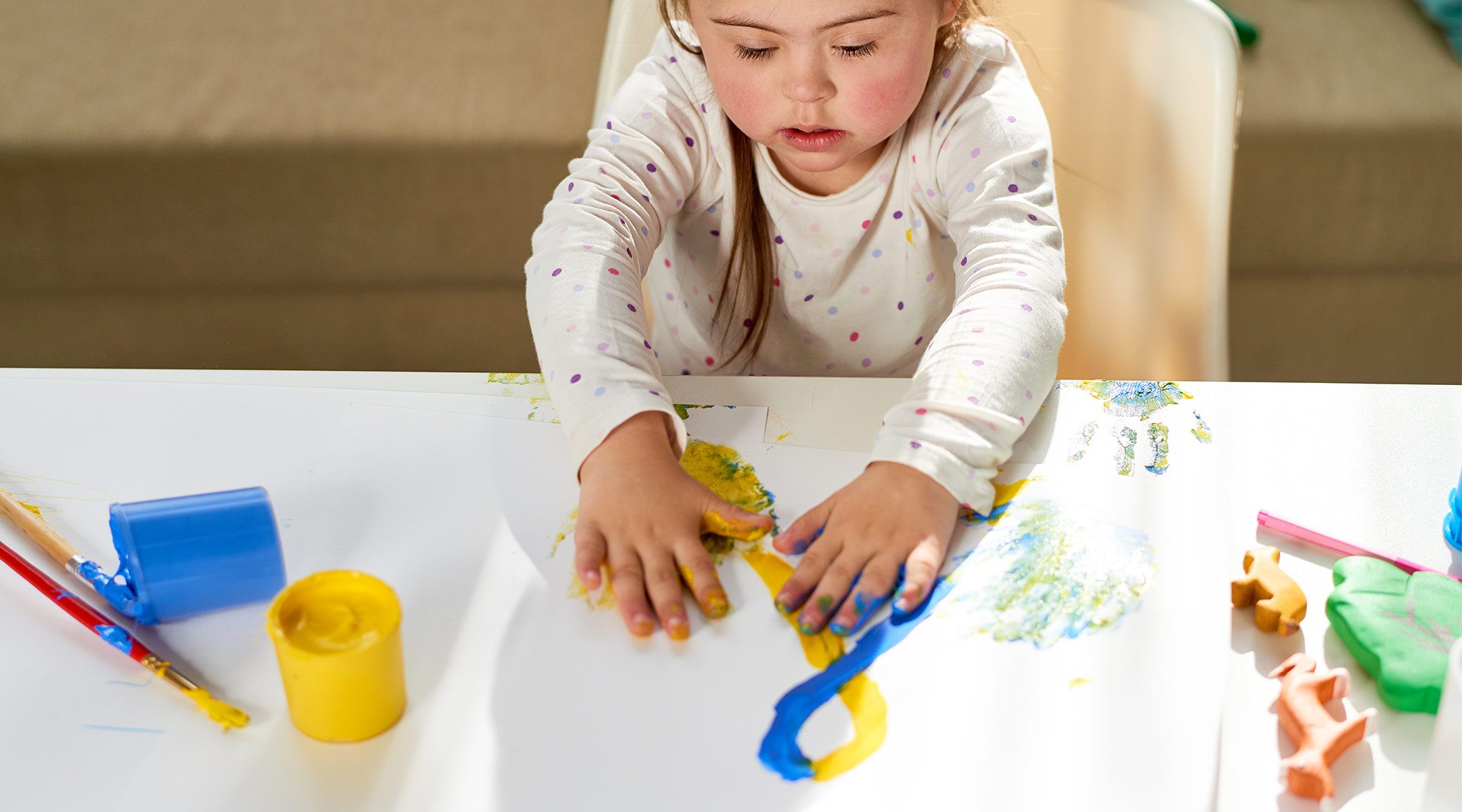 toddler using paint to make art at table