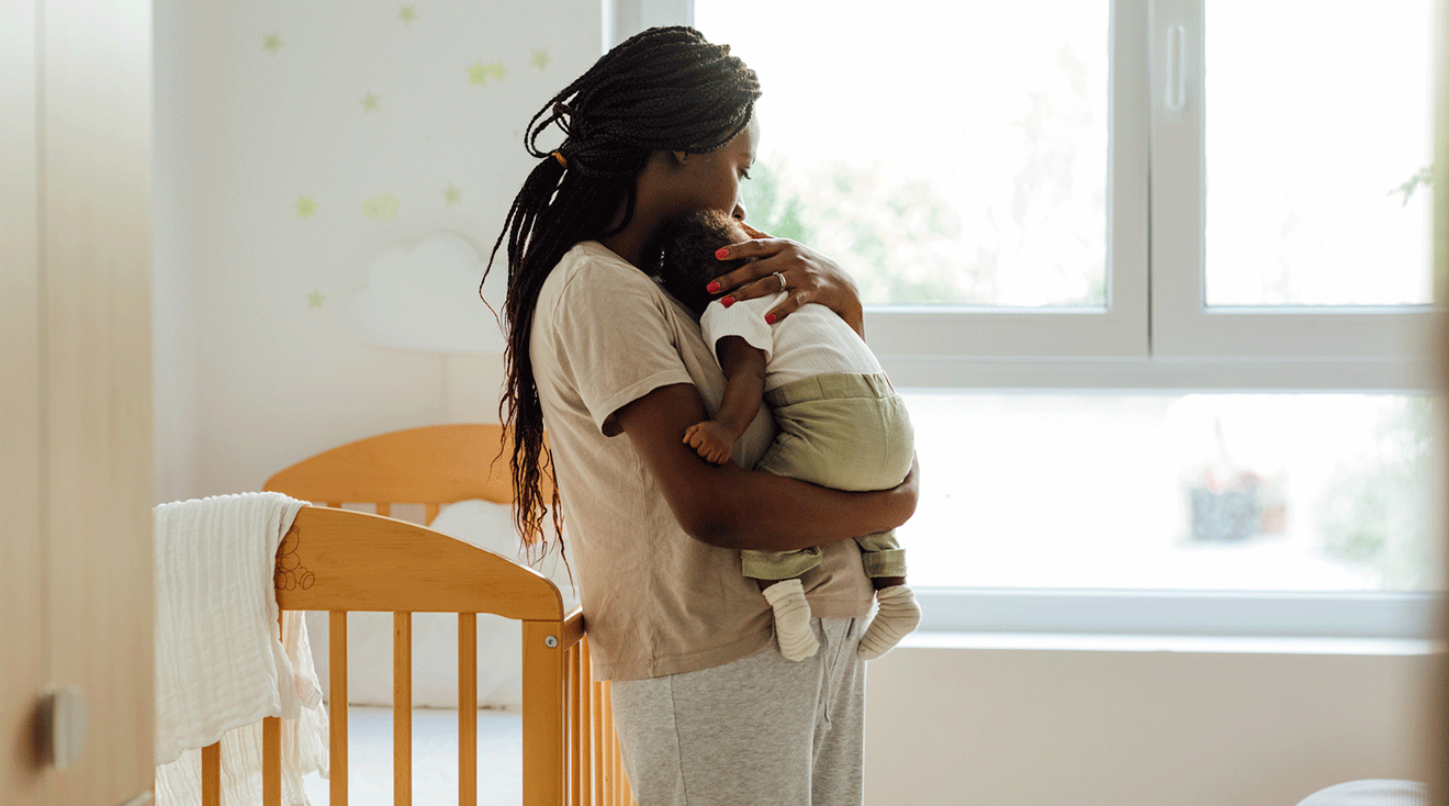 mom holding newborn baby in nursery during the day