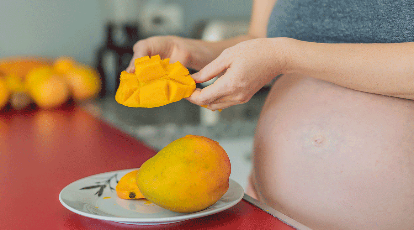 pregnant woman cutting a mango