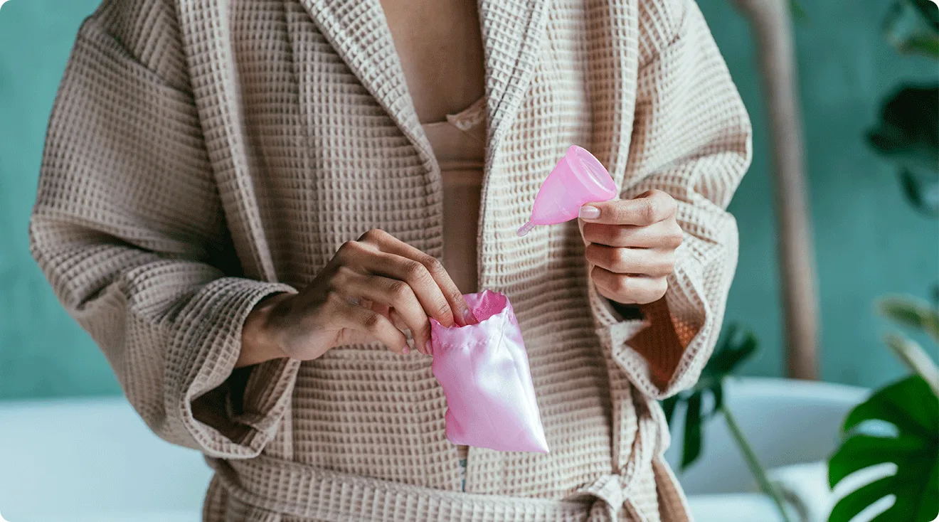 woman in robe holding menstrual cup in bathroom