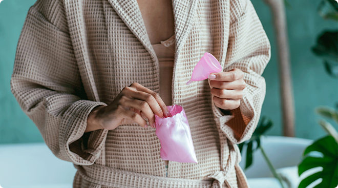 woman in robe holding menstrual cup in bathroom