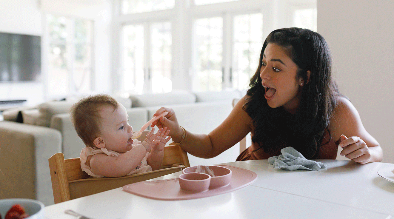 mom feeding baby food in high chair at home