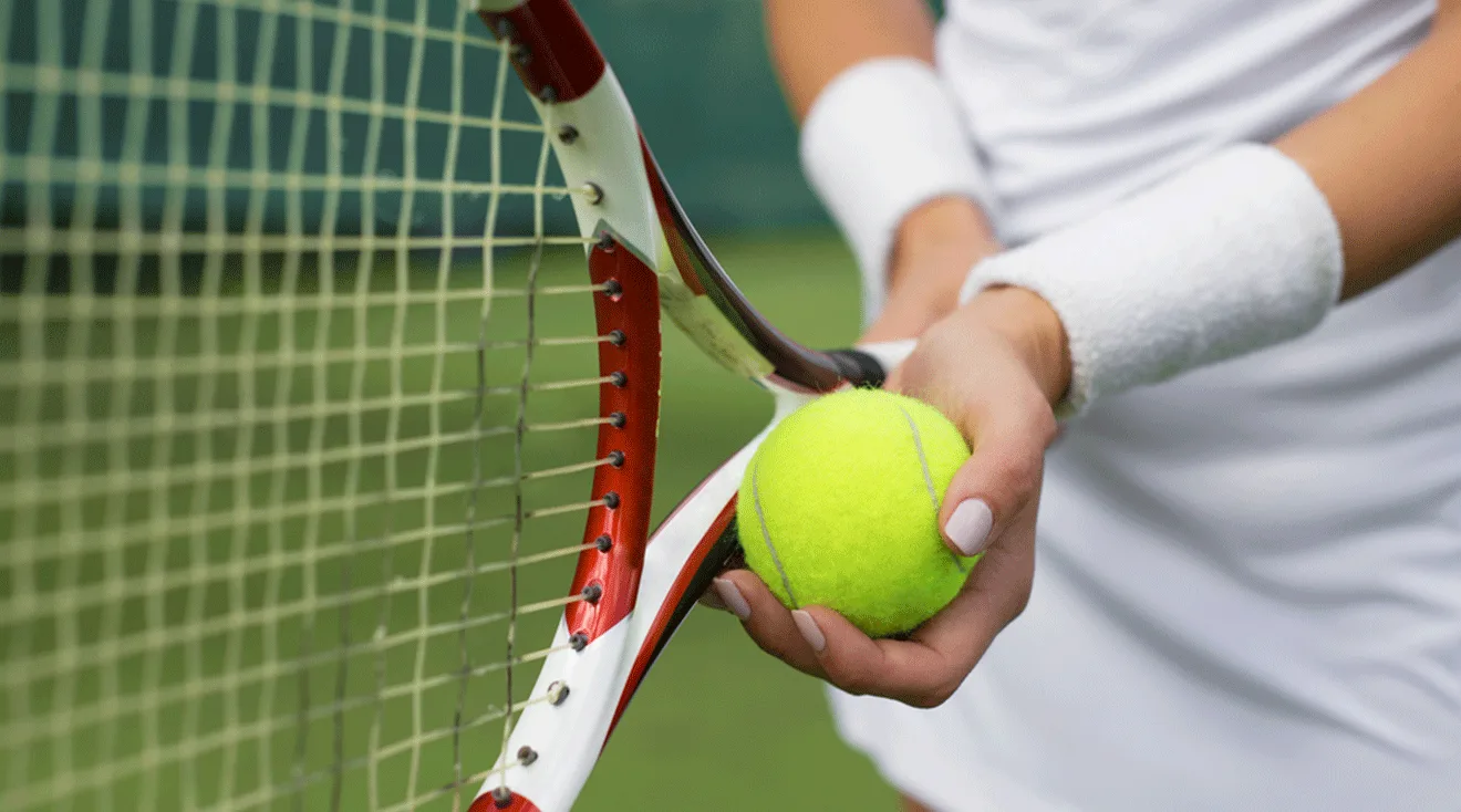 close up of woman holding tennis racket and tennis ball