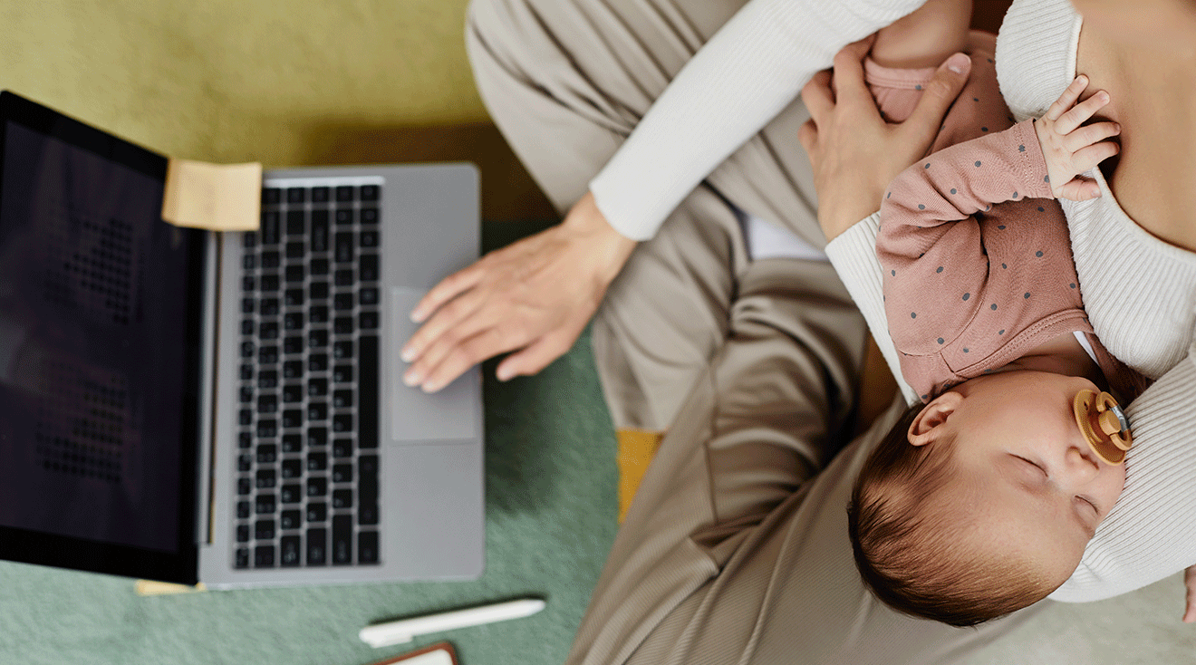 mom holding baby and using laptop at home