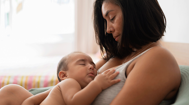mother holding sleeping baby at home
