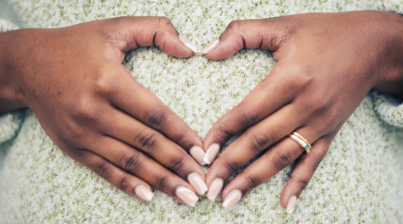 pregnant woman with hands in heart shape over belly