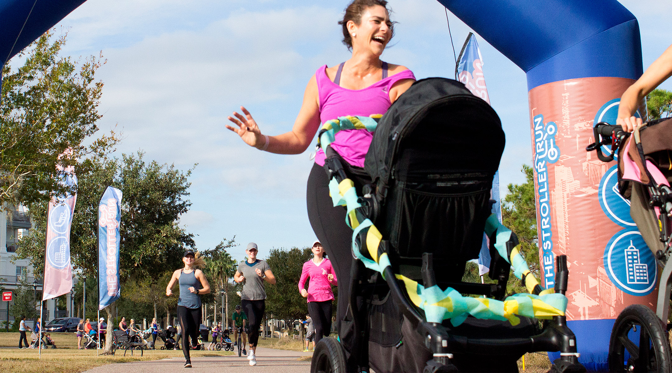 happy mom crossing the finish line of the stroller 5k run