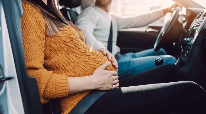 man driving pregnant woman in car to hospital for labor and delivery