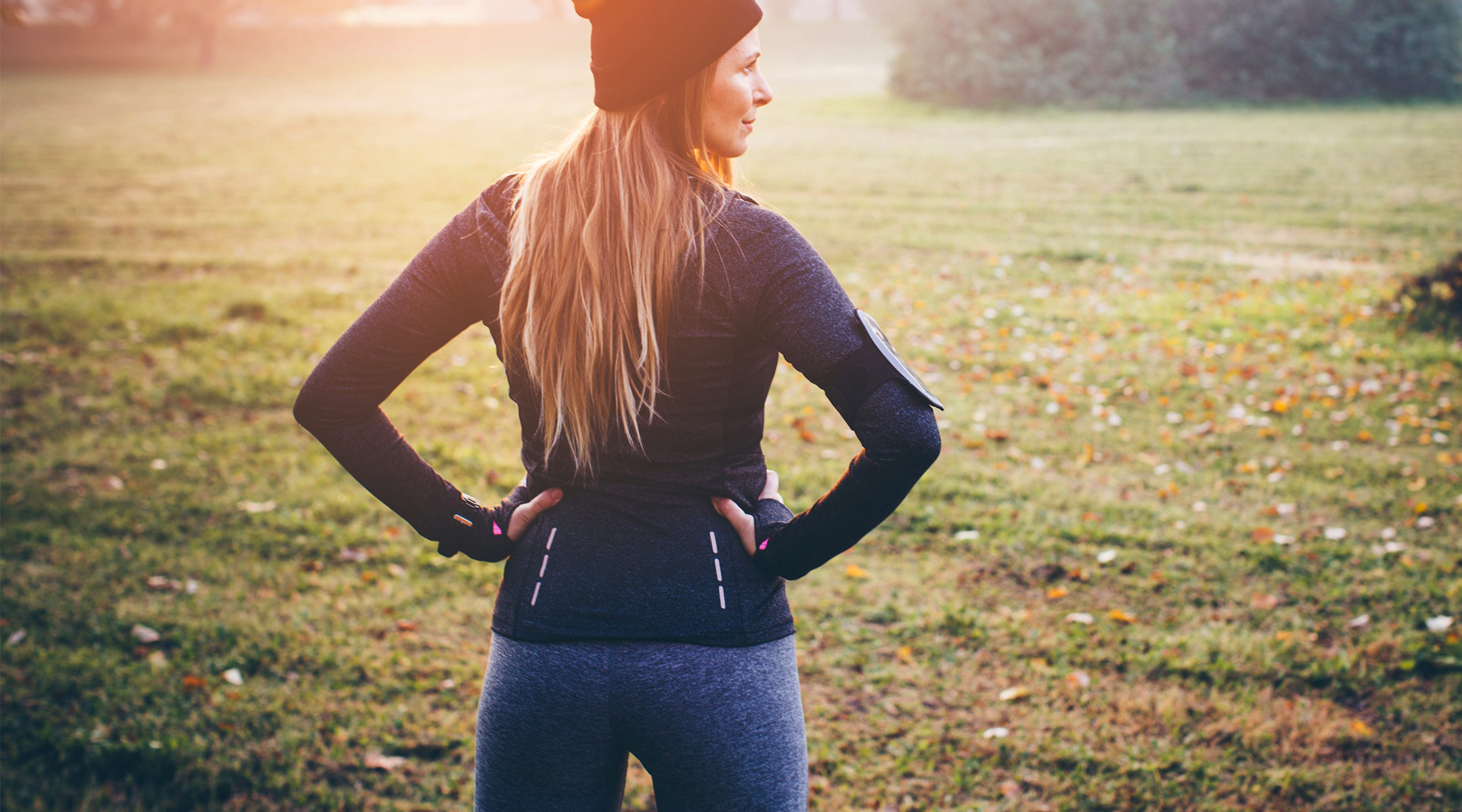 proud smiling woman stands outside in work out clothes