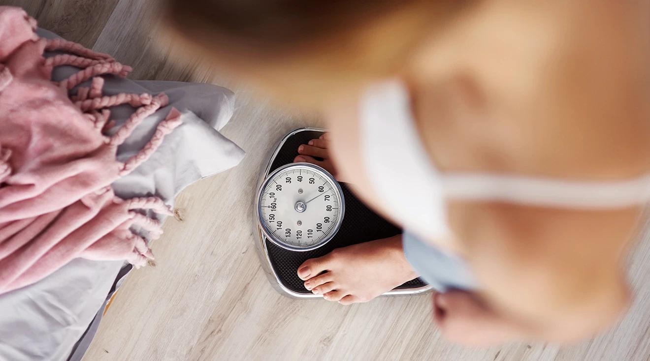 pregnant woman weighing herself on scale at home